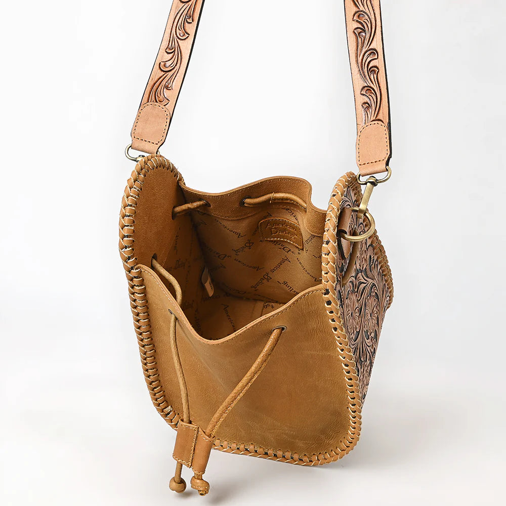 American Darling Western Floral Tooled Leather Sling Bag. Brown leather bag with intricate floral patterns on a white background