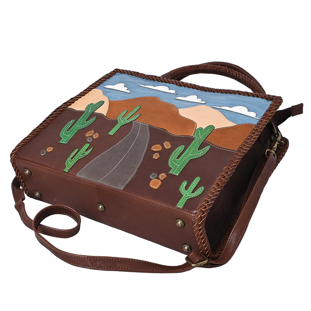 American Darling Desert Road Applique Western Tote. Brown leather bag with desert landscape design featuring cacti and mountains on a white background