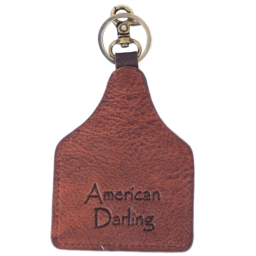 American Darling White key fob with brown feather design and metal ring on a white background