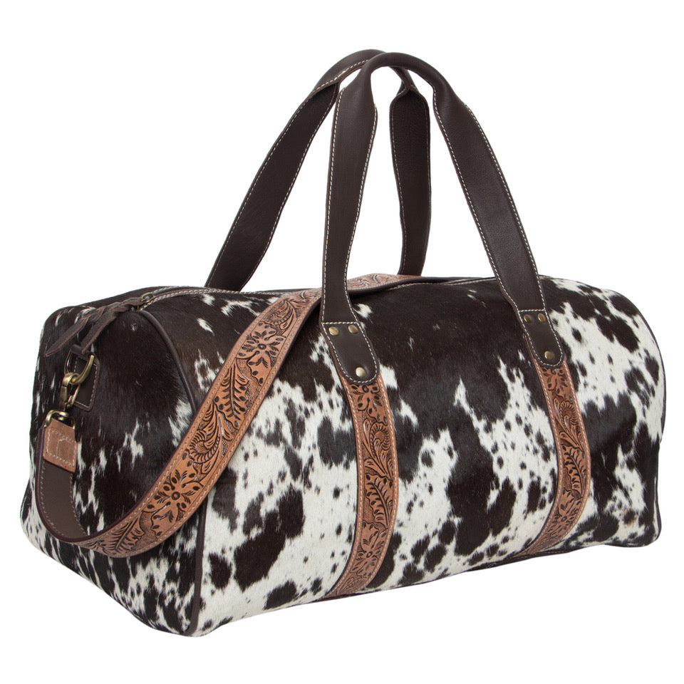 Columbia Tooling Leather Cowhide Travel Bag. Duffle bag with cow print pattern and brown leather accents on a white background