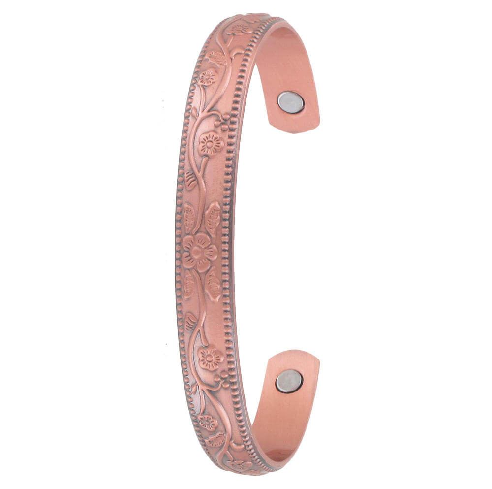 Floral Raised Copper Magnetic Band. A floral raised copper magnetic therapy cuff bracelet with a pinkish hue and clasp mechanism on the side.