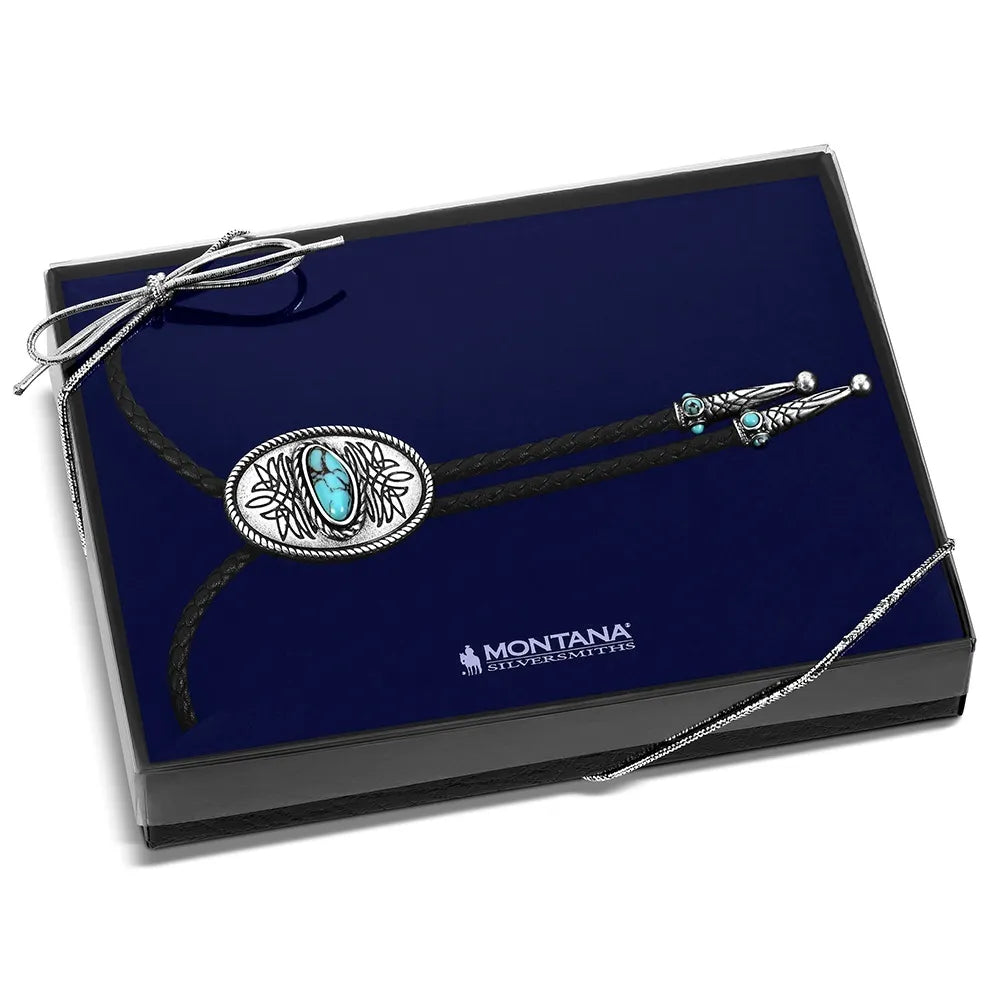 A Montana Western-style concho bolo necklace with a turquoise stone, presented in a black gift box with a blue velvet insert. The necklace features a silver concho button and a matching silver cord tie with a turquoise accent.