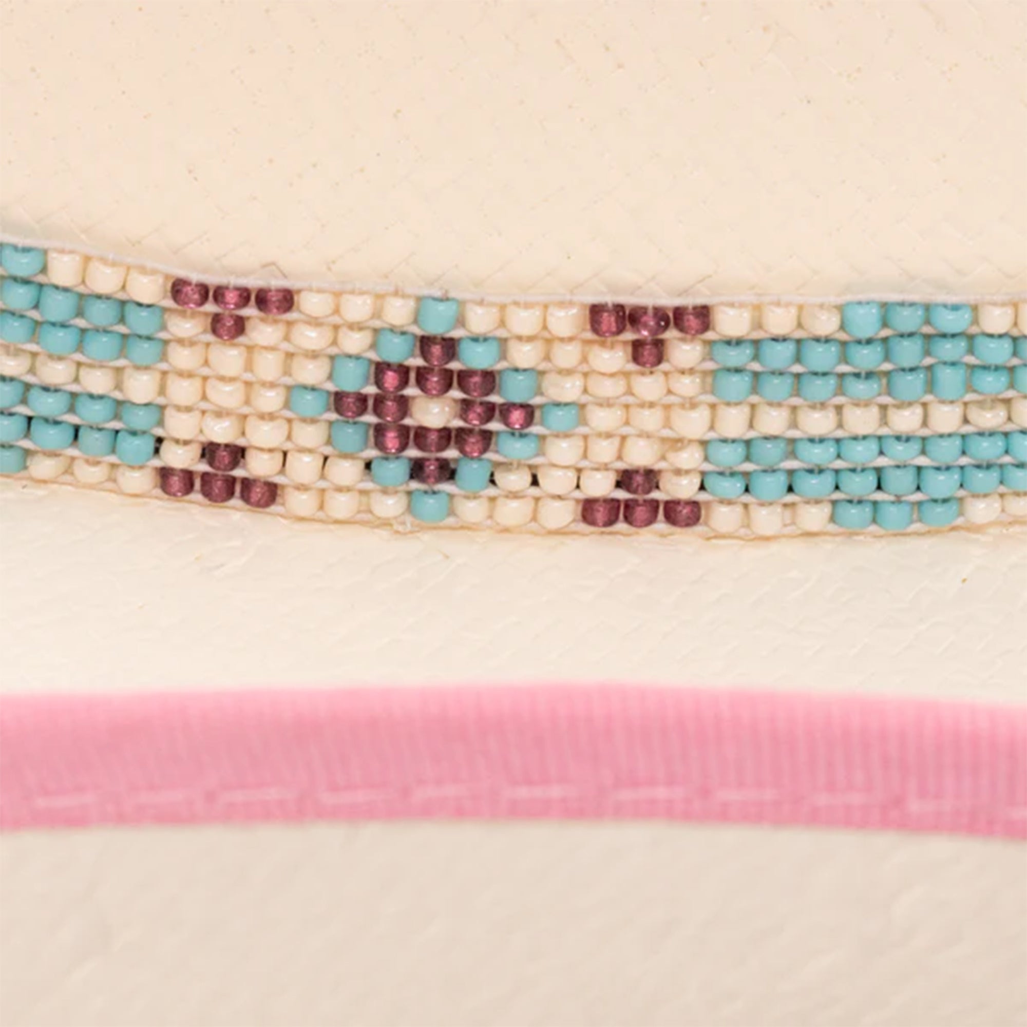 Charlie 1 Horse Gracie JR Straw Cowboy Hat. Close-up of a beaded ribbon with pink ribbon underneath on a beige background
