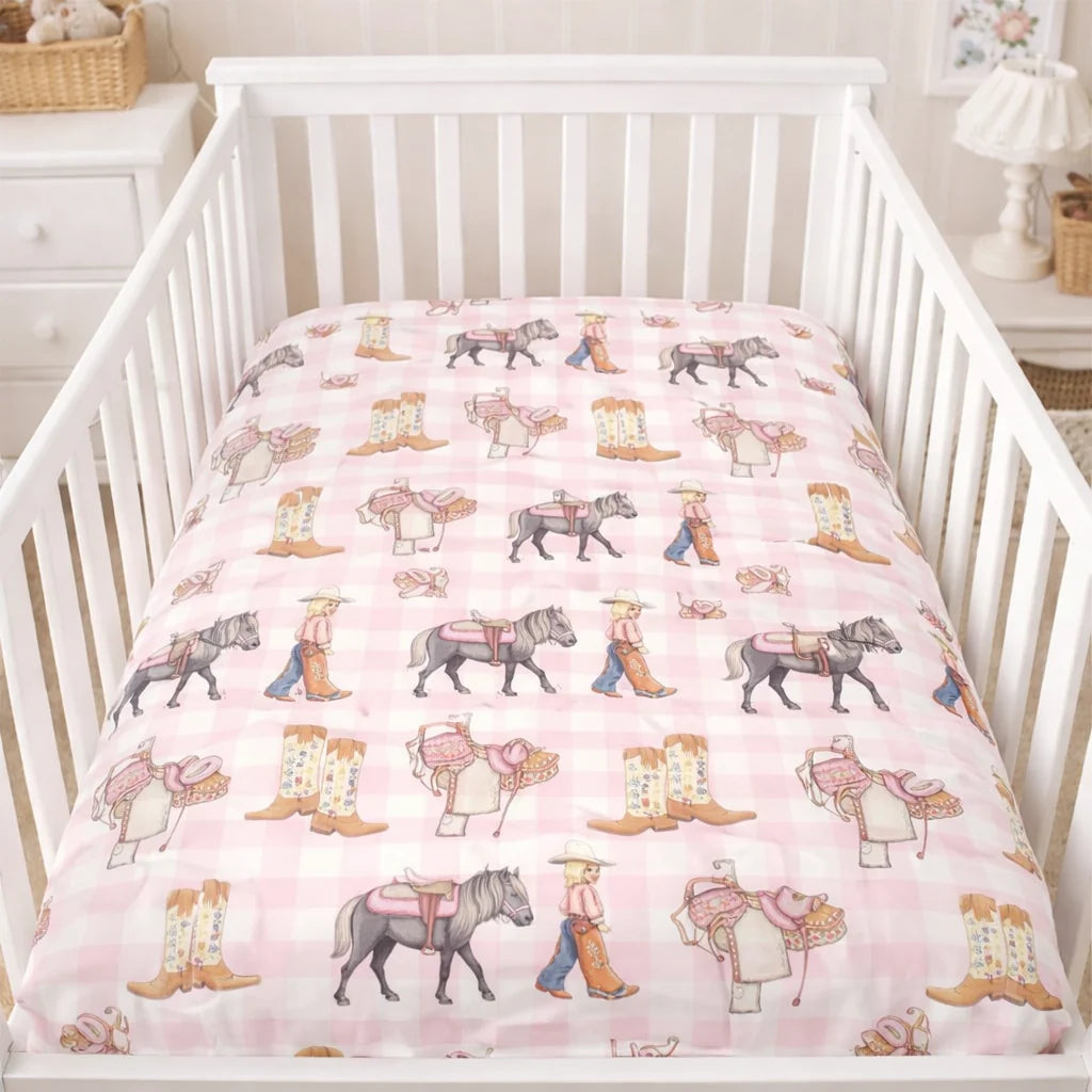 Crib with pink bedding featuring horse and cowboy patterns