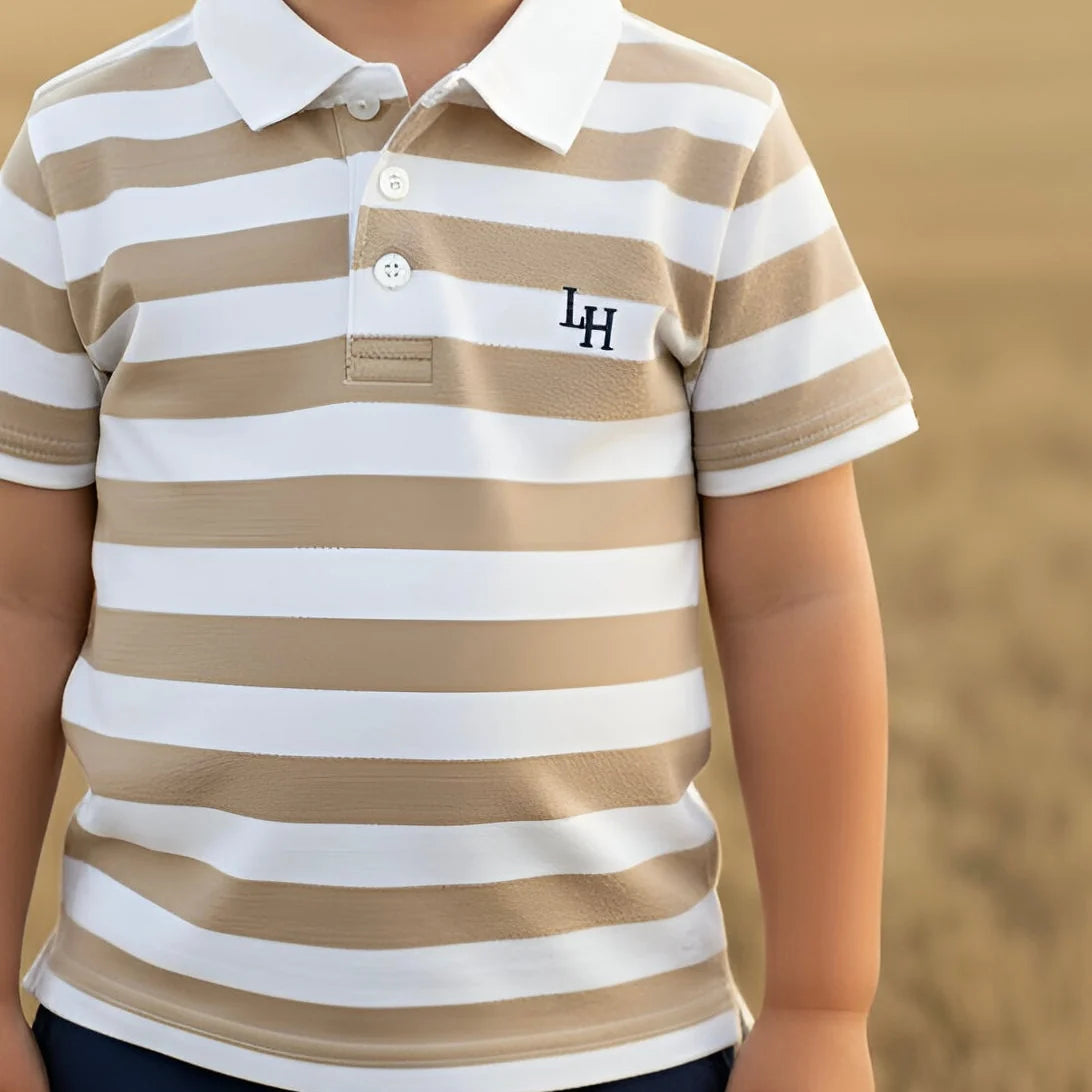 A close-up of a child wearing a short-sleeve polo shirt with horizontal beige and white stripes and a black embroidered 'LH' logo on the chest, set against a blurred sandy background.