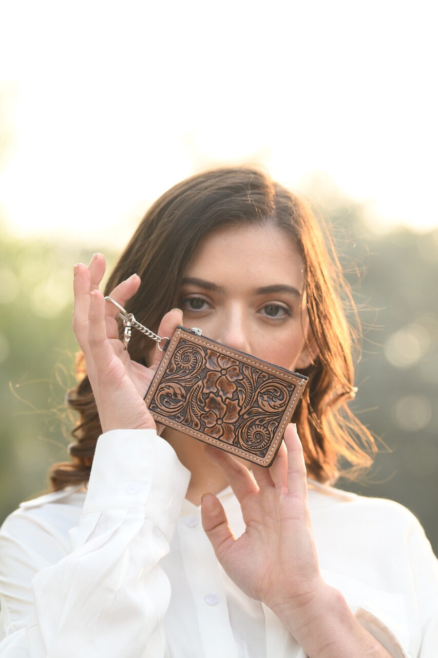 Tooling Leather Key/ Card Case. Woman holding a brown leather wallet with intricate designs outdoors.