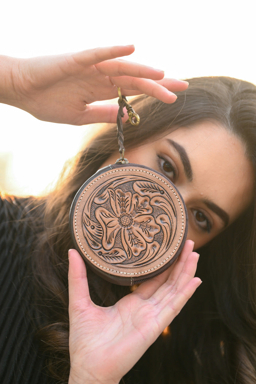 Tooling Leather Round Purse. Person holding a round, intricately designed leather pouch with floral patterns.