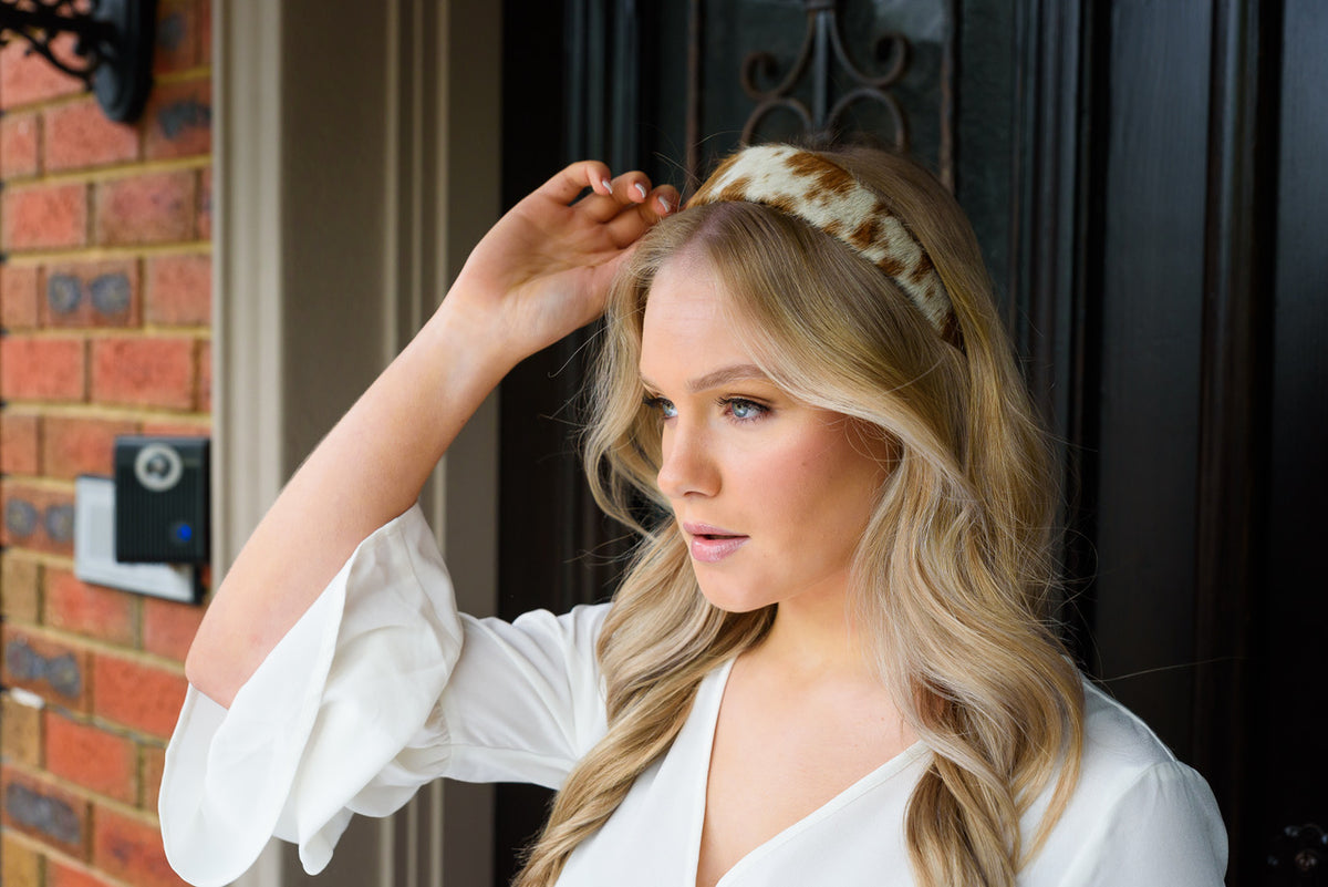 Cowhide Hairband. Woman adjusting a headband in front of a door with a brick wall background