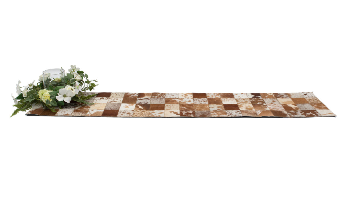 Cowhide Table Runner. Checkered cowhide table runner with floral arrangement on a white background