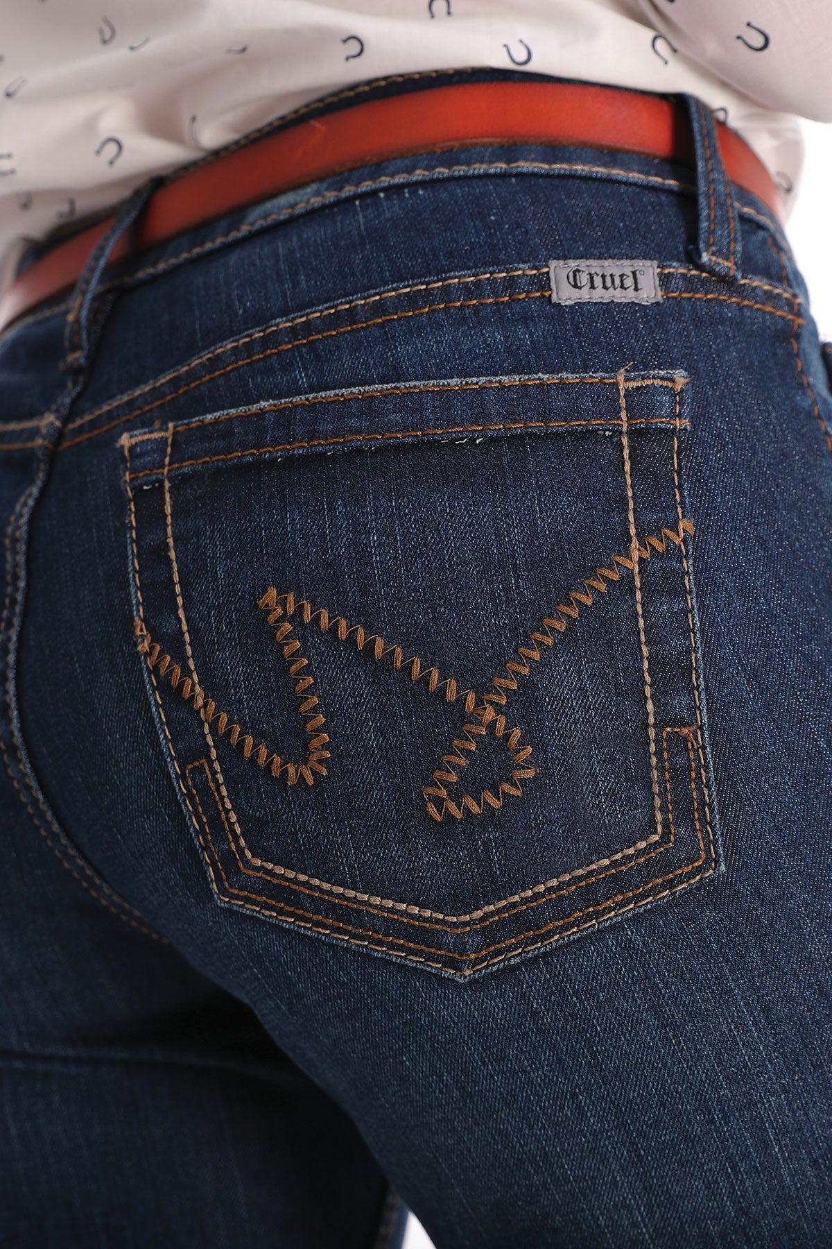 Cruel Denim Women's Hannah Slim Fit Jean. Close-up of blue jeans with a brand label on the pocket against a white background