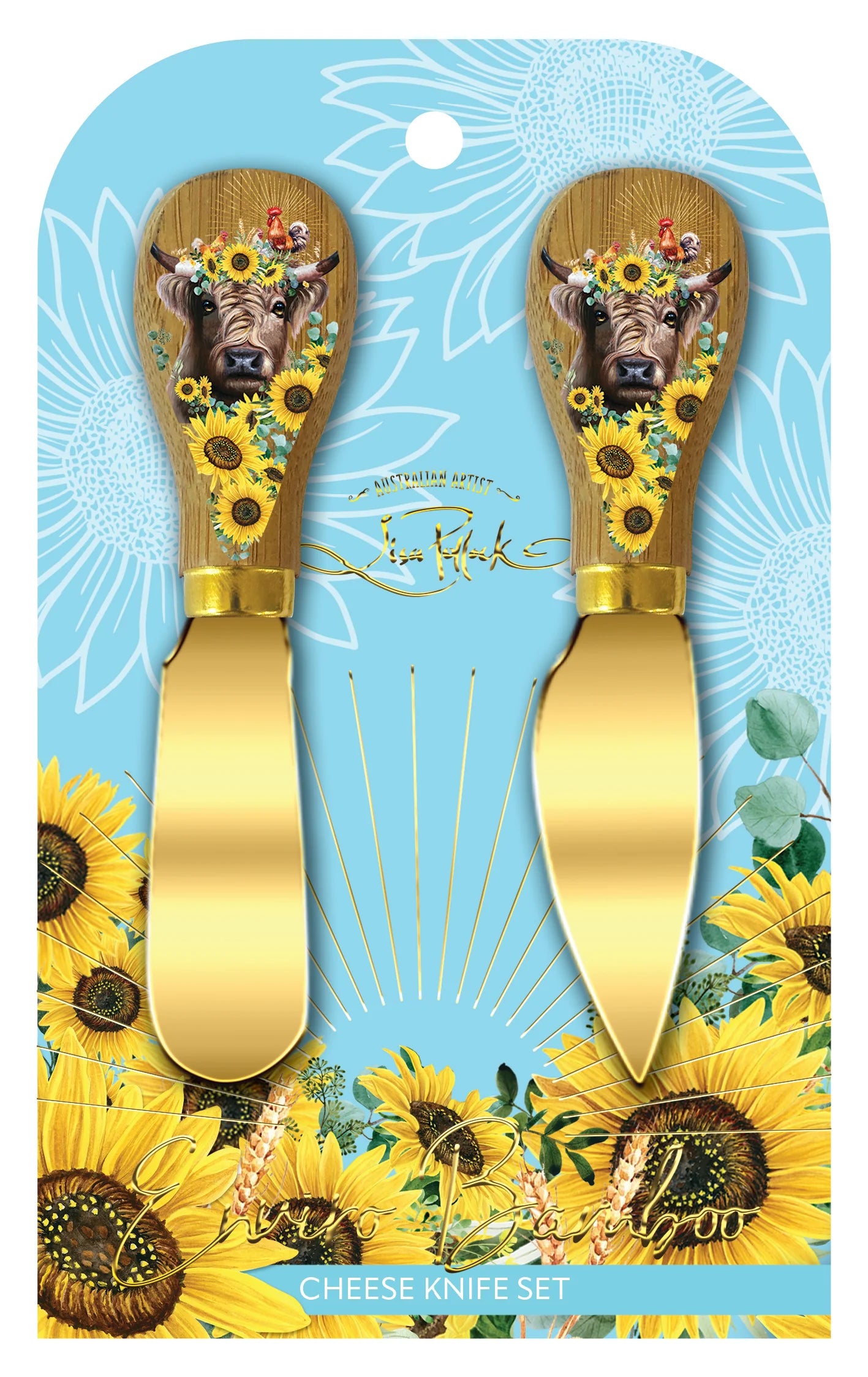 Lisa Pollock Sunny Highland Cheese Knives. Two cheese knives with decorative handles featuring bulls and sunflowers, on a blue packaging background with sunflower design.