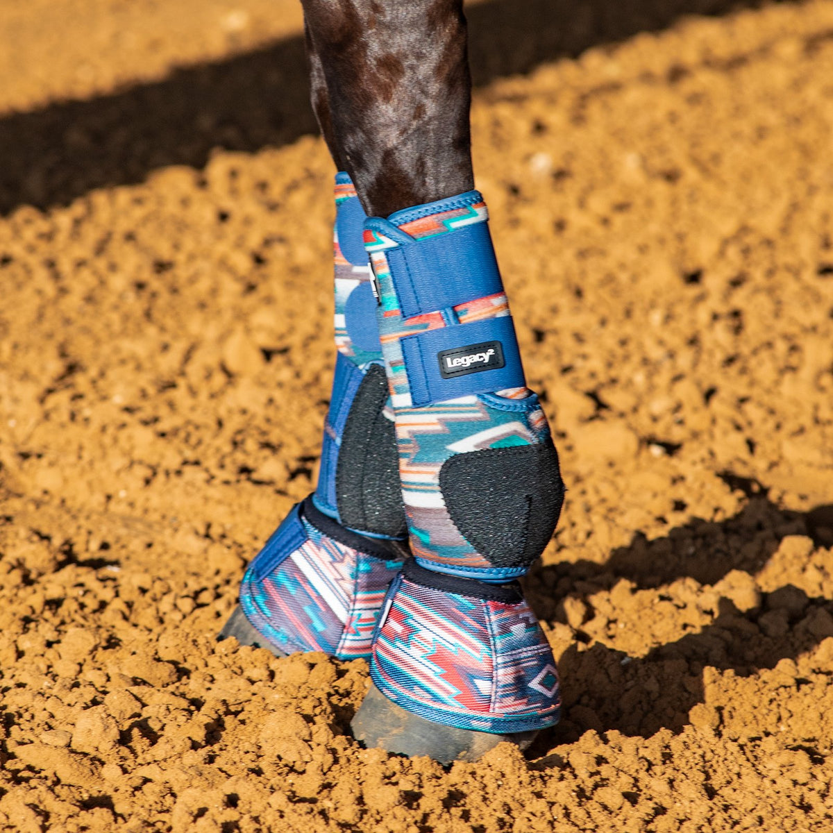 Classic Equine Legacy2 Pueblo Full Set Support Boots. Horse's hoof with blue protective boot on a dirt ground