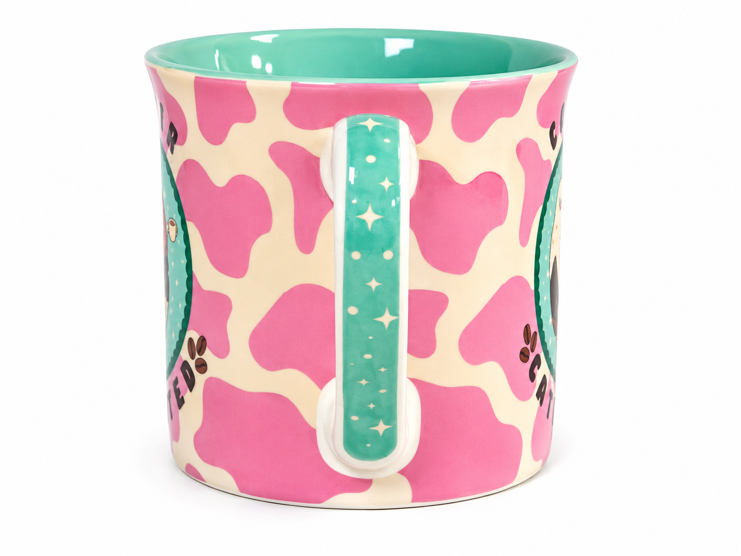 A ceramic mug with a pink and cream cow print pattern, featuring a turquoise handle and interior, decorated with cartoon owl illustrations.