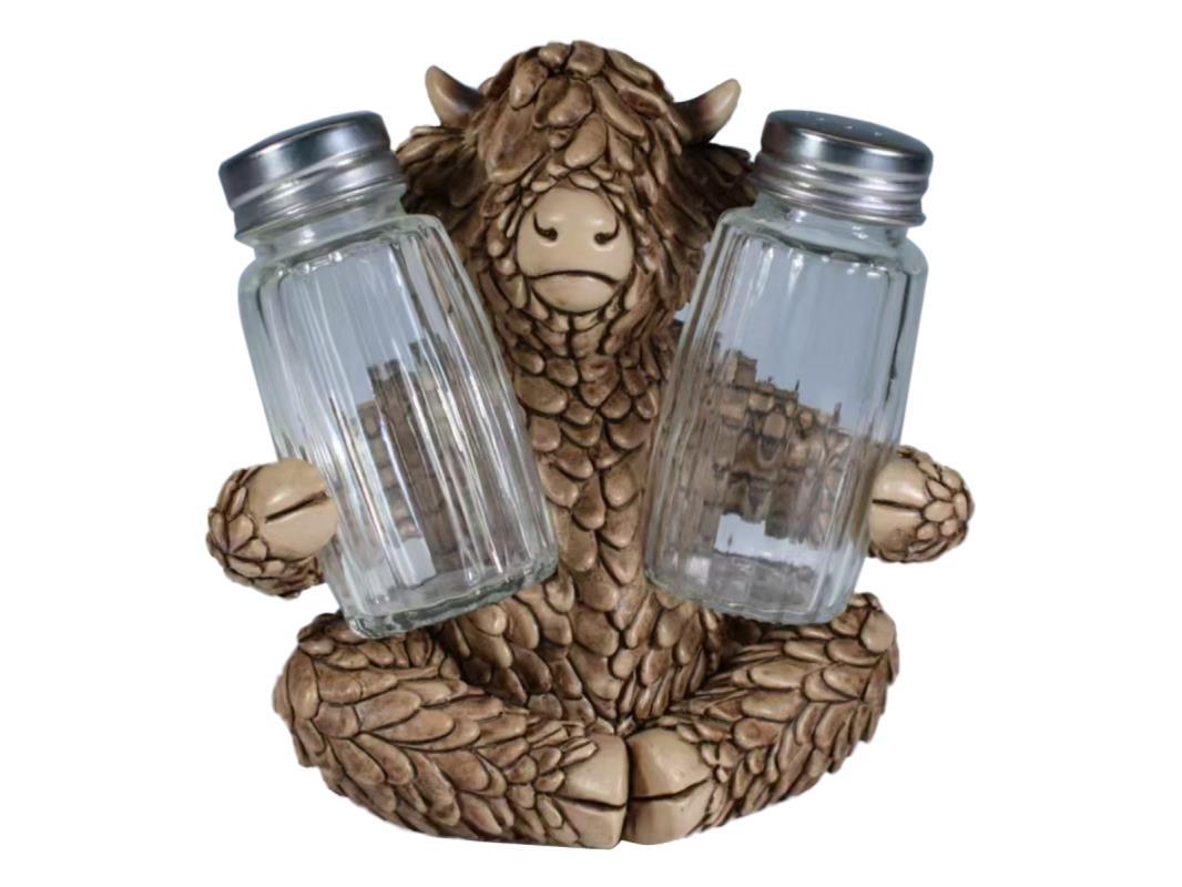 Statue of a creature holding two glass salt and pepper shakers on a white background