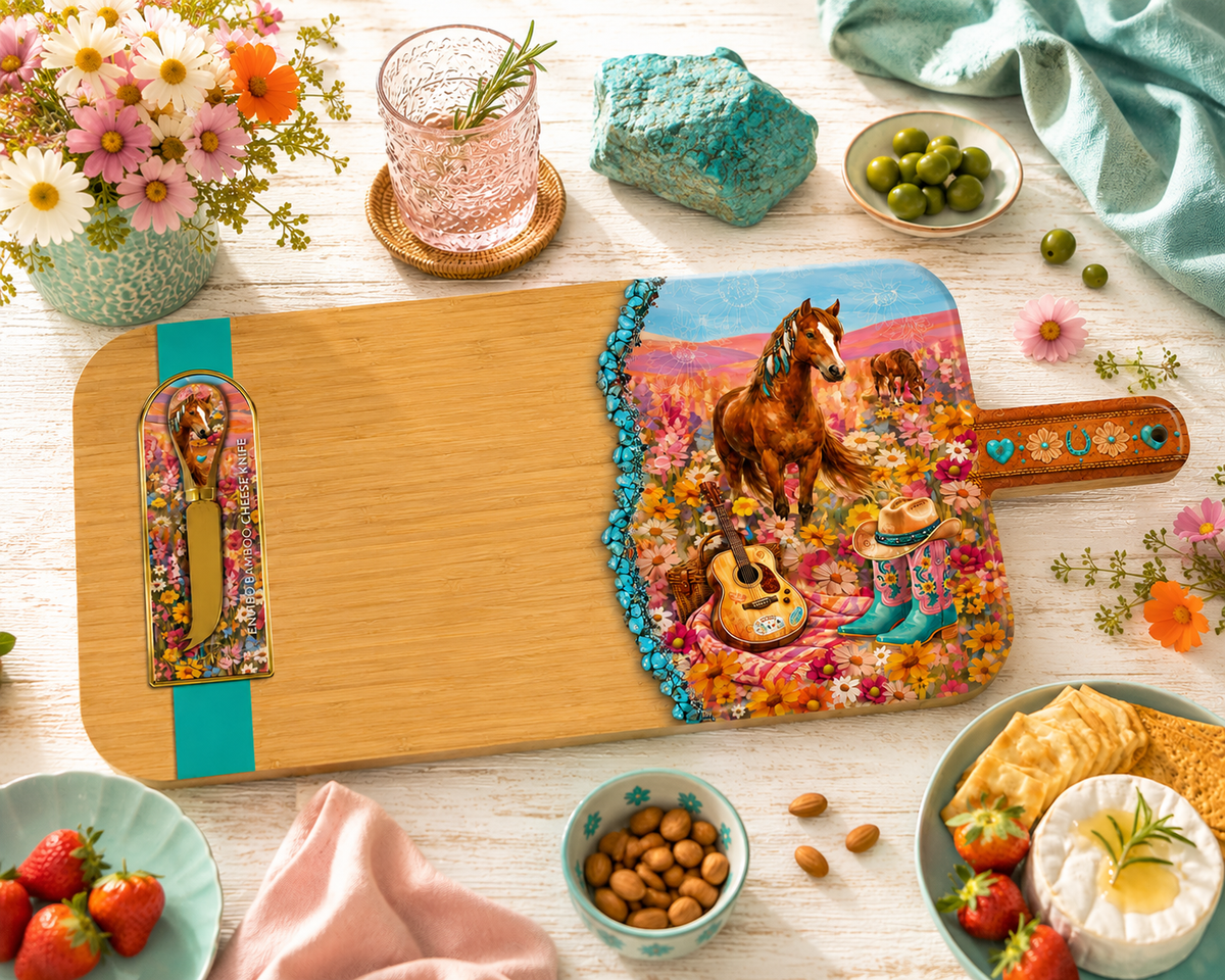 A wooden serving board with a colorful printed design of a horse, guitar, flowers, and turquoise accents, styled on a white tabletop with snacks, flowers, and drinkware around it.