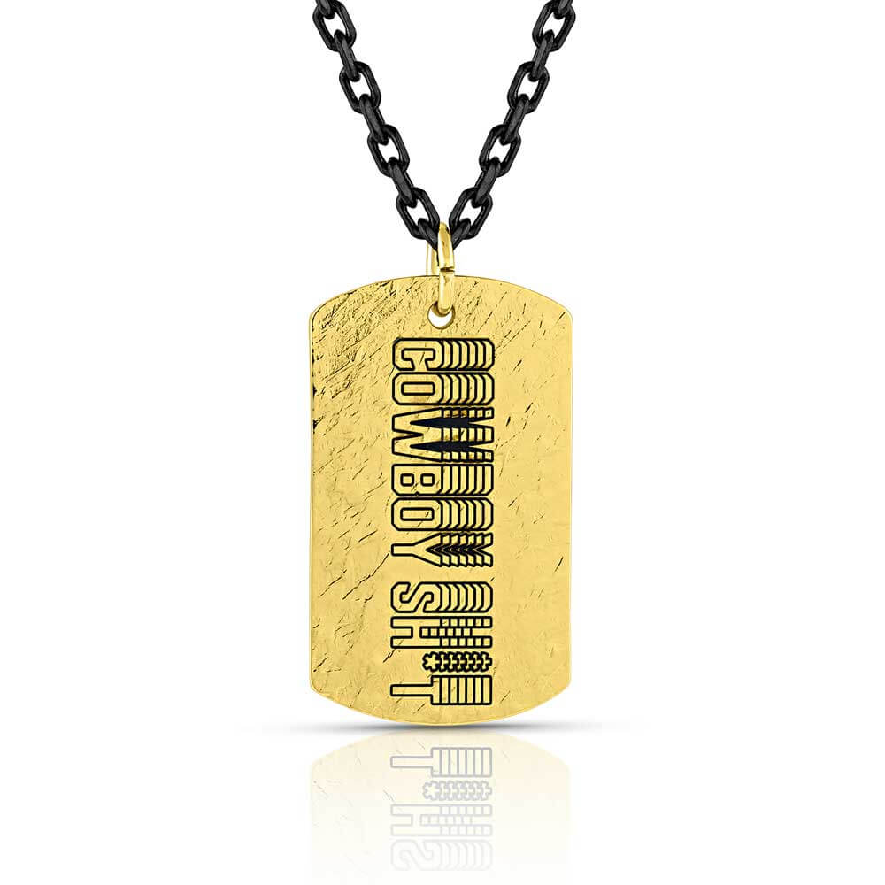 Montana Silversmiths Cowboy Sh*t Gold Dog Tag Necklace. A gold dog tag necklace with the inscription 'Cowboy Sh*t' on a chain.