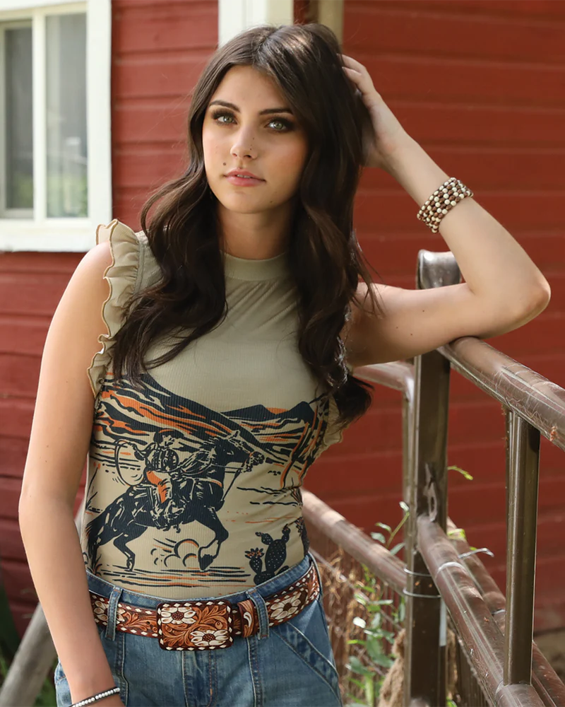 Woman wearing a sleeveless top with graphic design and jeans, standing outdoors.