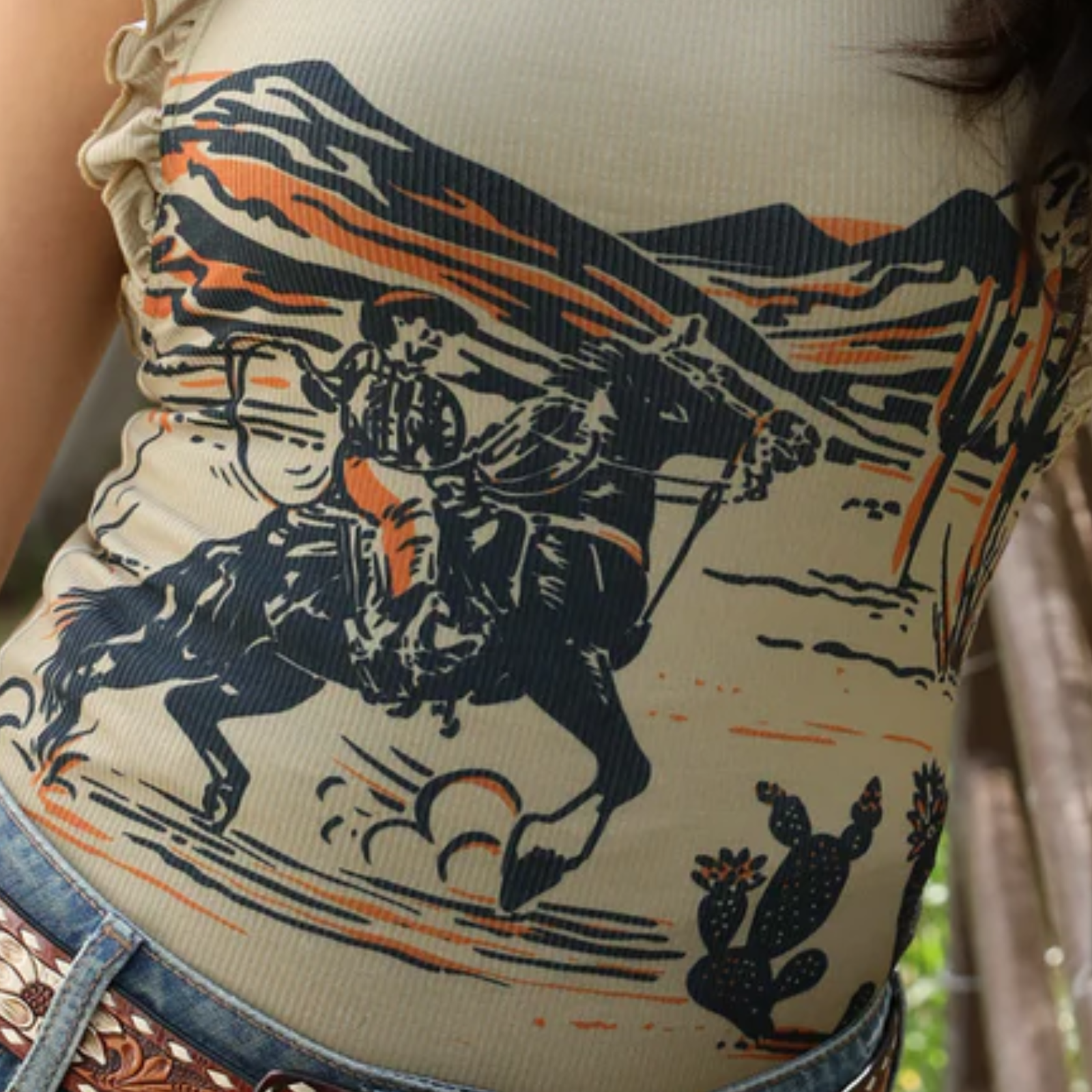 Close-up of a person wearing a tank top with a cowboy and horse design.