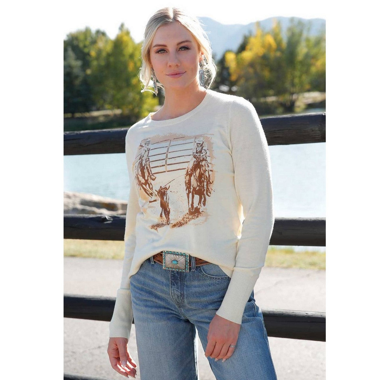 Cruel Denim Women's Roper Graphic Lightweight Sweater. Woman wearing a cream sweater with horse print outdoors
