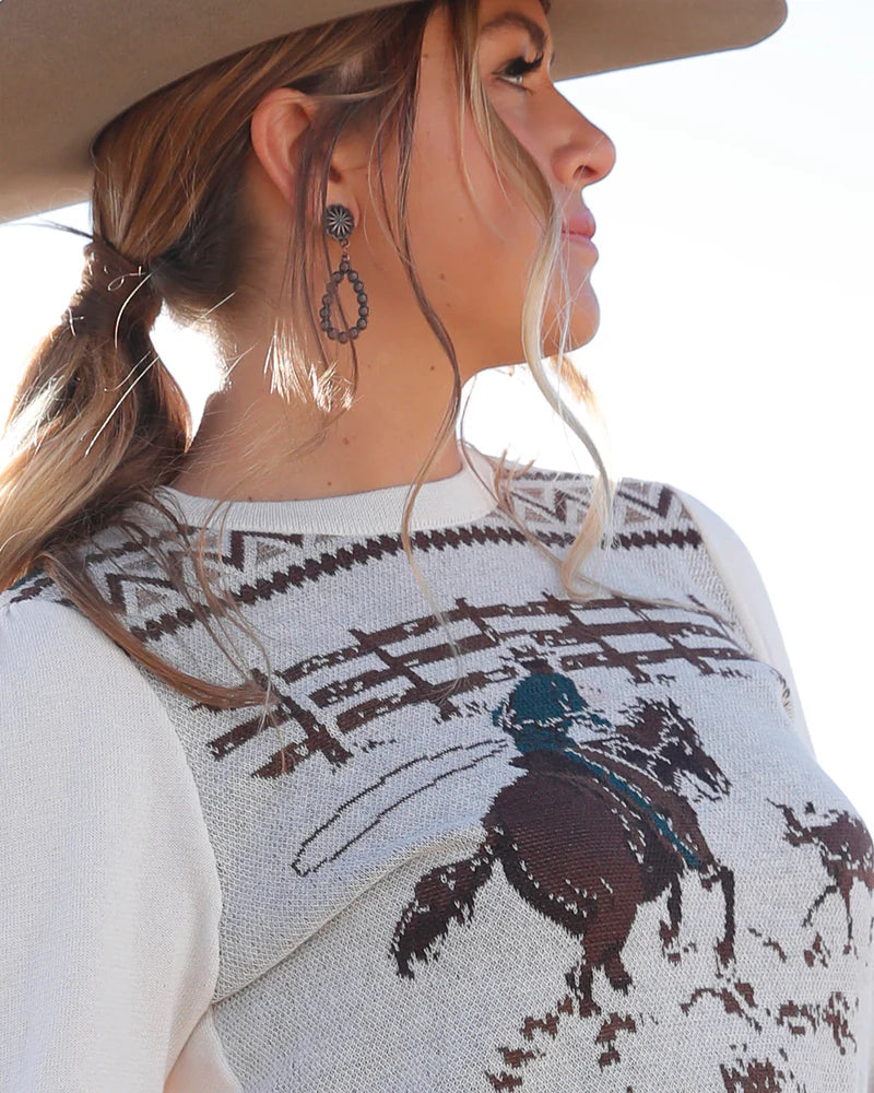 Woman wearing a cowboy hat and a patterned shirt with a horse design.