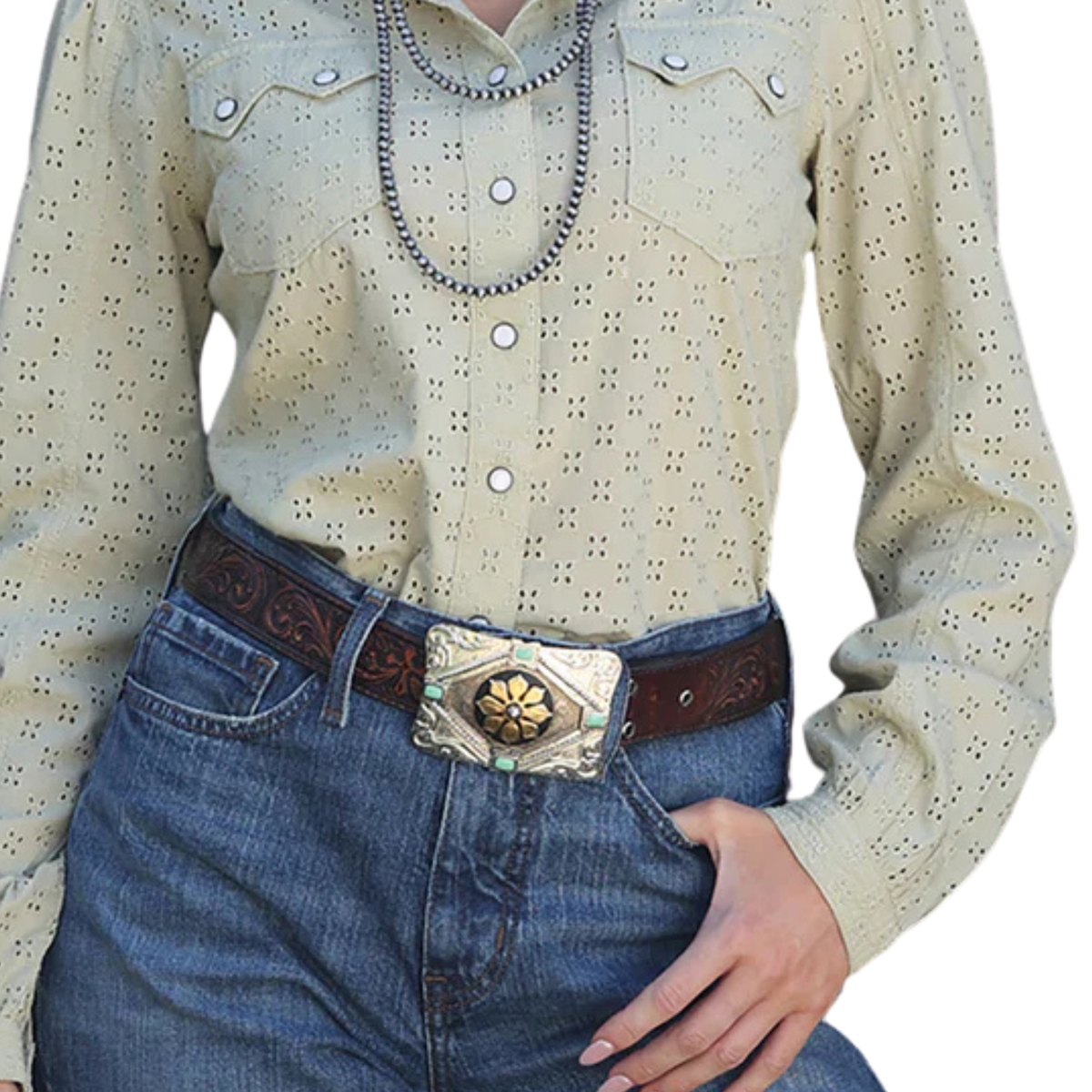 Person wearing a beige long-sleeve shirt with button details and blue jeans with a decorative belt.