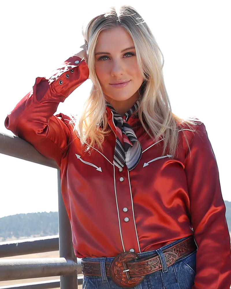 Woman wearing a red western-style shirt with a scenic background