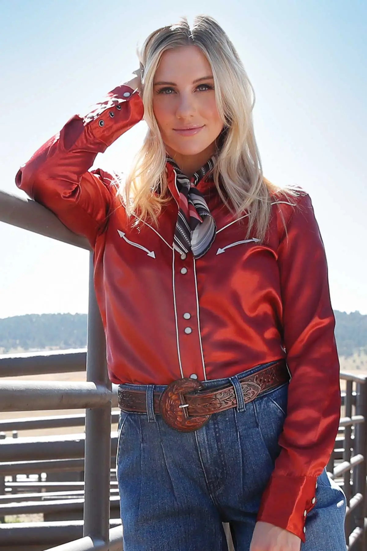 Cruel Denim Women's Vintage L/S Western Shirt. Woman wearing a red western-style shirt and blue jeans with a scarf, standing outdoors.