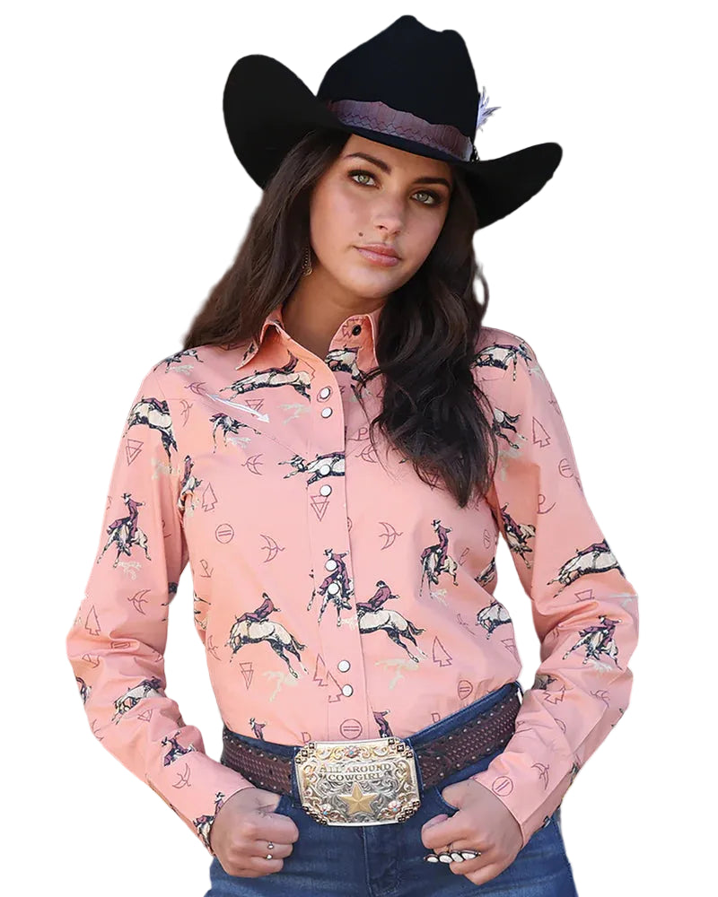 Woman wearing a pink patterned shirt and black cowboy hat in an outdoor setting