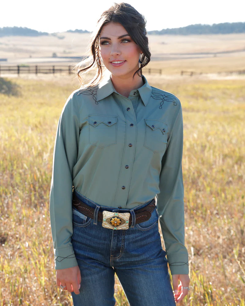 Woman wearing a green long-sleeve shirt with decorative stitching in a field