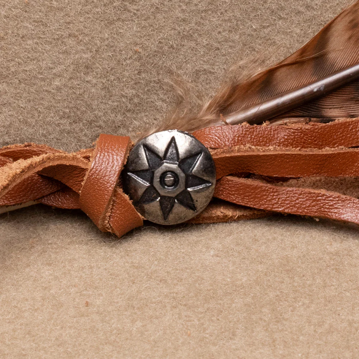 Charlie 1 Horse Wanderlust Felt Cowboy Hat. A beige wool cowboy hat with a bubble crown and a brim, featuring a woven hatband with a silver side concho and a feather, and the Charlie 1 Horse brand logo on the crown.