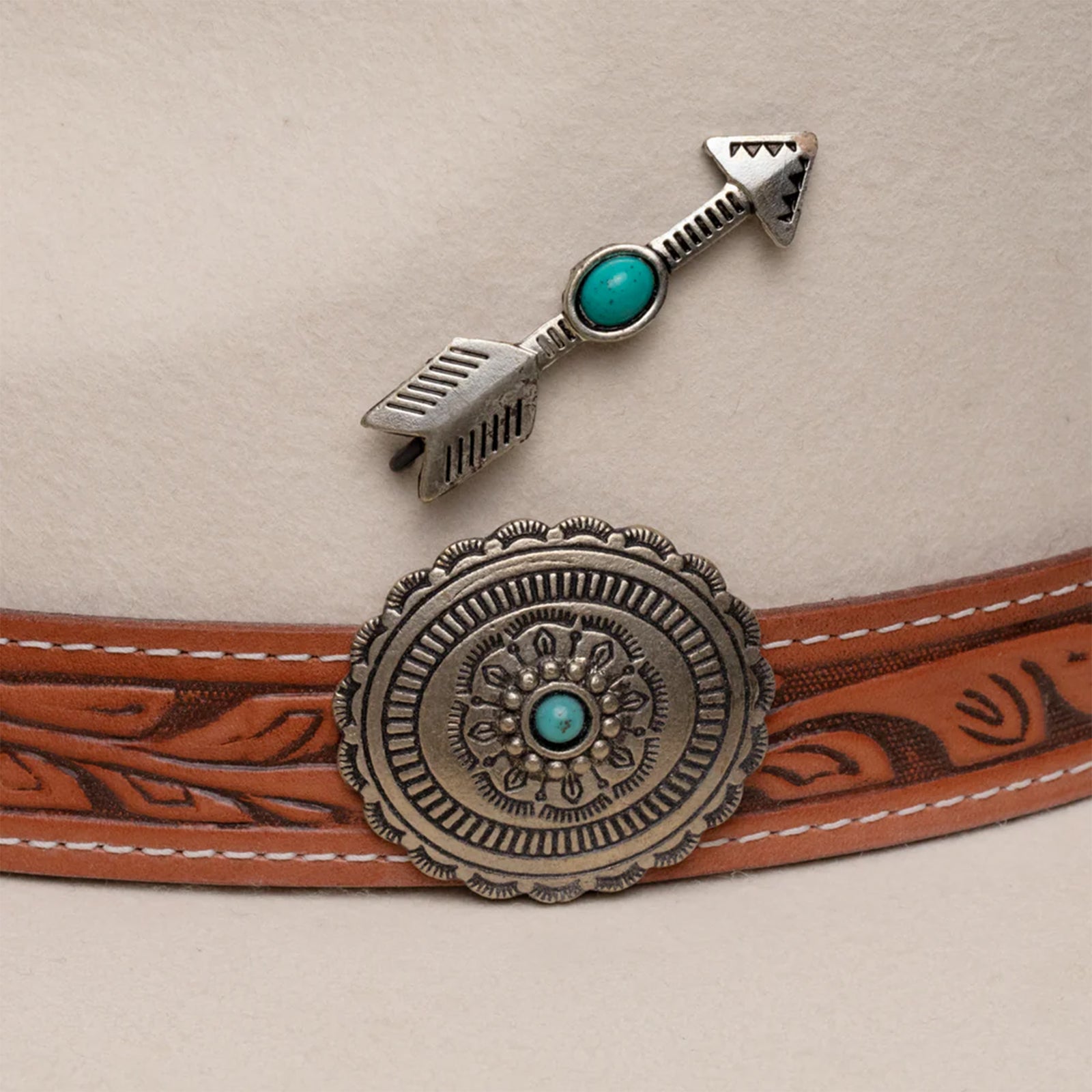 Charlie 1 Horse White Sands Felt Cowboy Hat. A beige felt cowboy hat with a leather-like hat band featuring metal-like and turquoise accents, and a metal-like arrow hat pin.