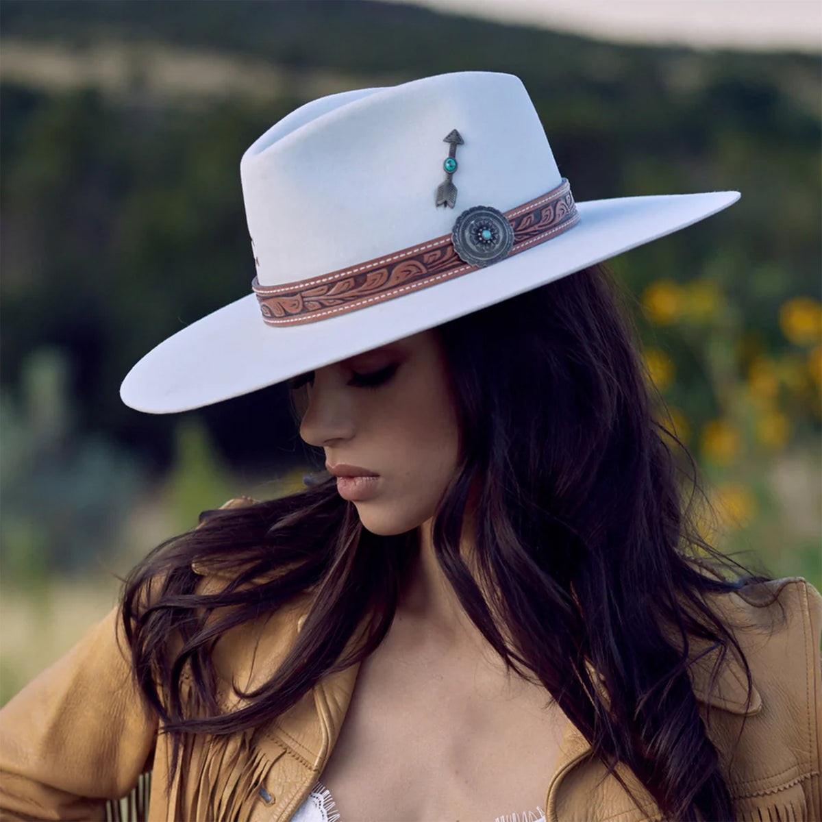 Charlie 1 Horse White Sands Felt Cowboy Hat. A beige felt cowboy hat with a leather-like hat band featuring metal-like and turquoise accents, and a metal-like arrow hat pin.