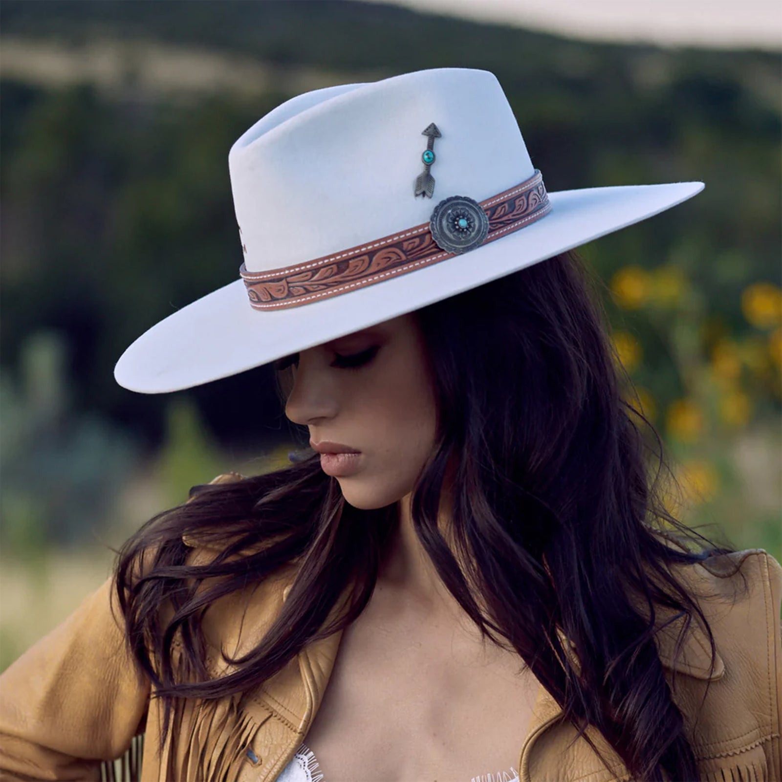 Charlie 1 Horse White Sands Felt Cowboy Hat. A beige felt cowboy hat with a leather-like hat band featuring metal-like and turquoise accents, and a metal-like arrow hat pin.