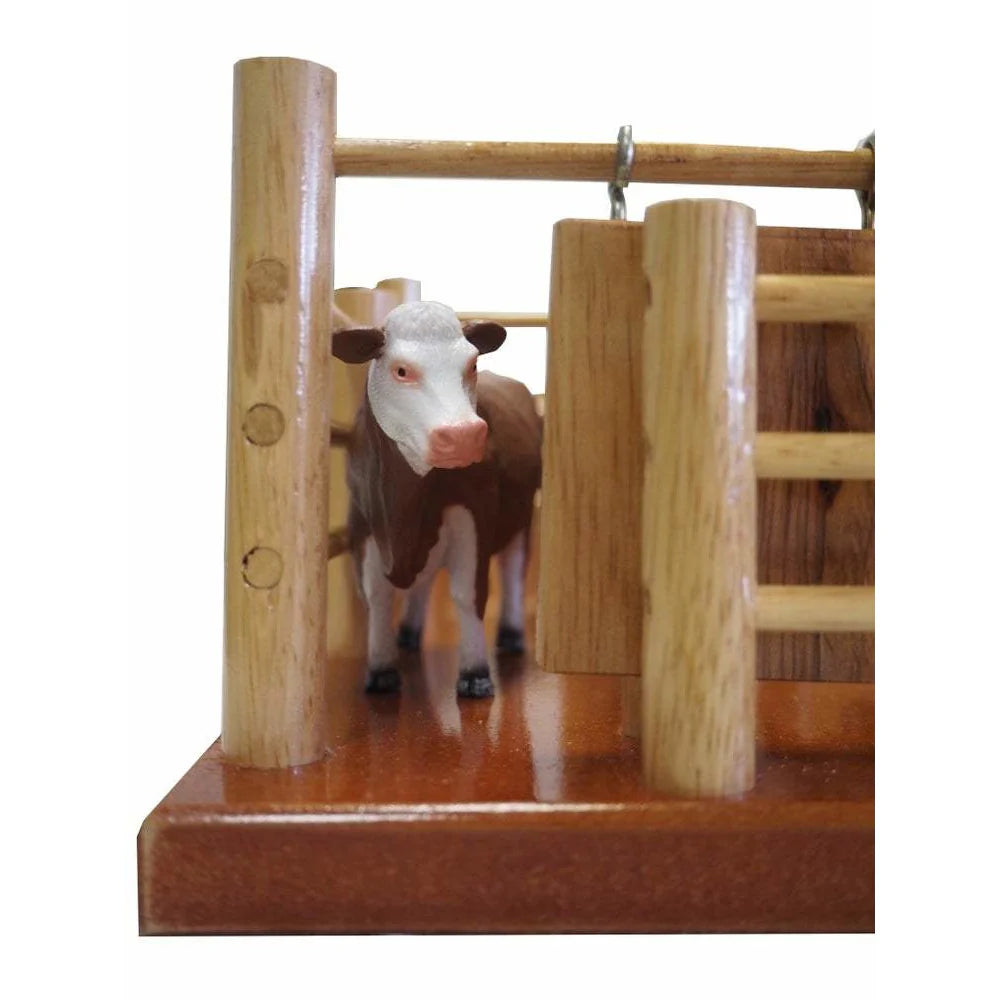 Country Toys CY8 Wooden Station Cattle Yard. Handmade wooden toy cattle yard with multiple gates, feed trough, water trough, and a metal branding cradle, displayed on a red surface.