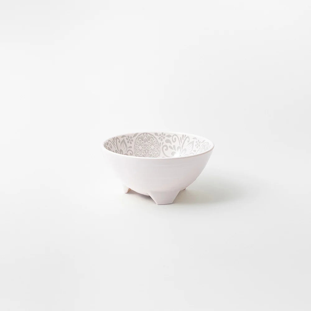 A small white ceramic bowl with a delicate gray floral pattern inside, standing on three short feet against a clean white background.