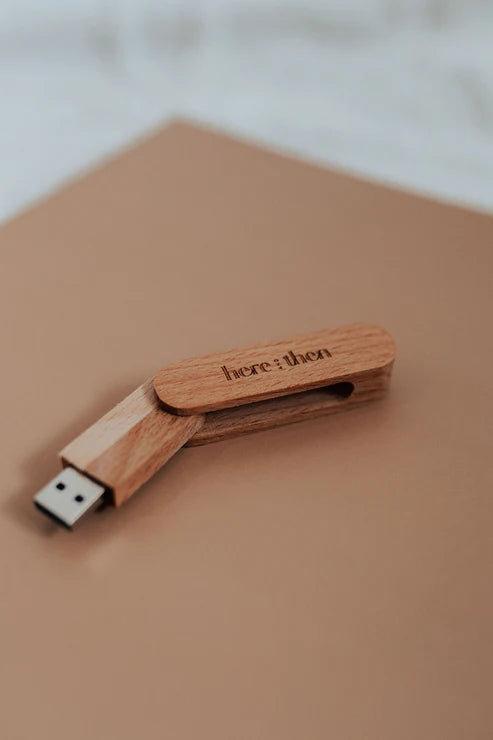 Here And Then Box - Natural. Wooden USB drive with 'here & then' branding on a beige surface