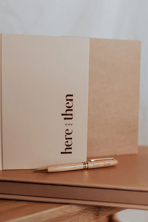 Here And Then Box - Burnt. Notebook with a pen on a wooden surface, featuring the text 'here then only'.