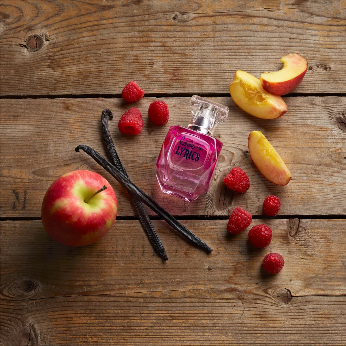 Pink perfume bottle surrounded by fruits and vanilla on a wooden surface