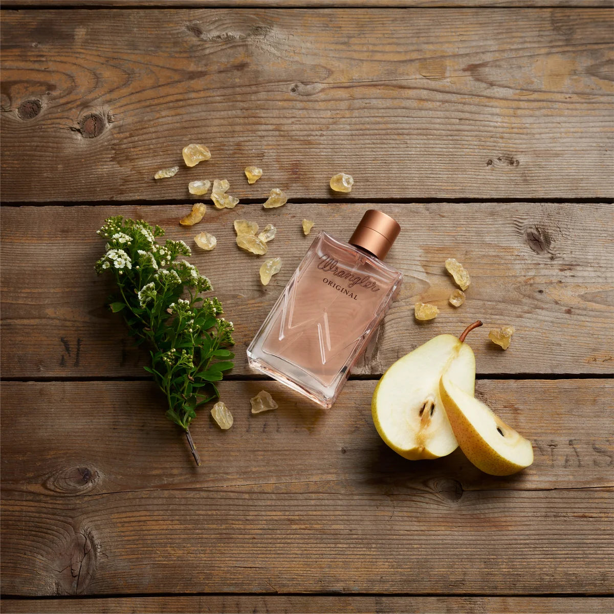 Perfume bottle with pear and flowers on a wooden surface