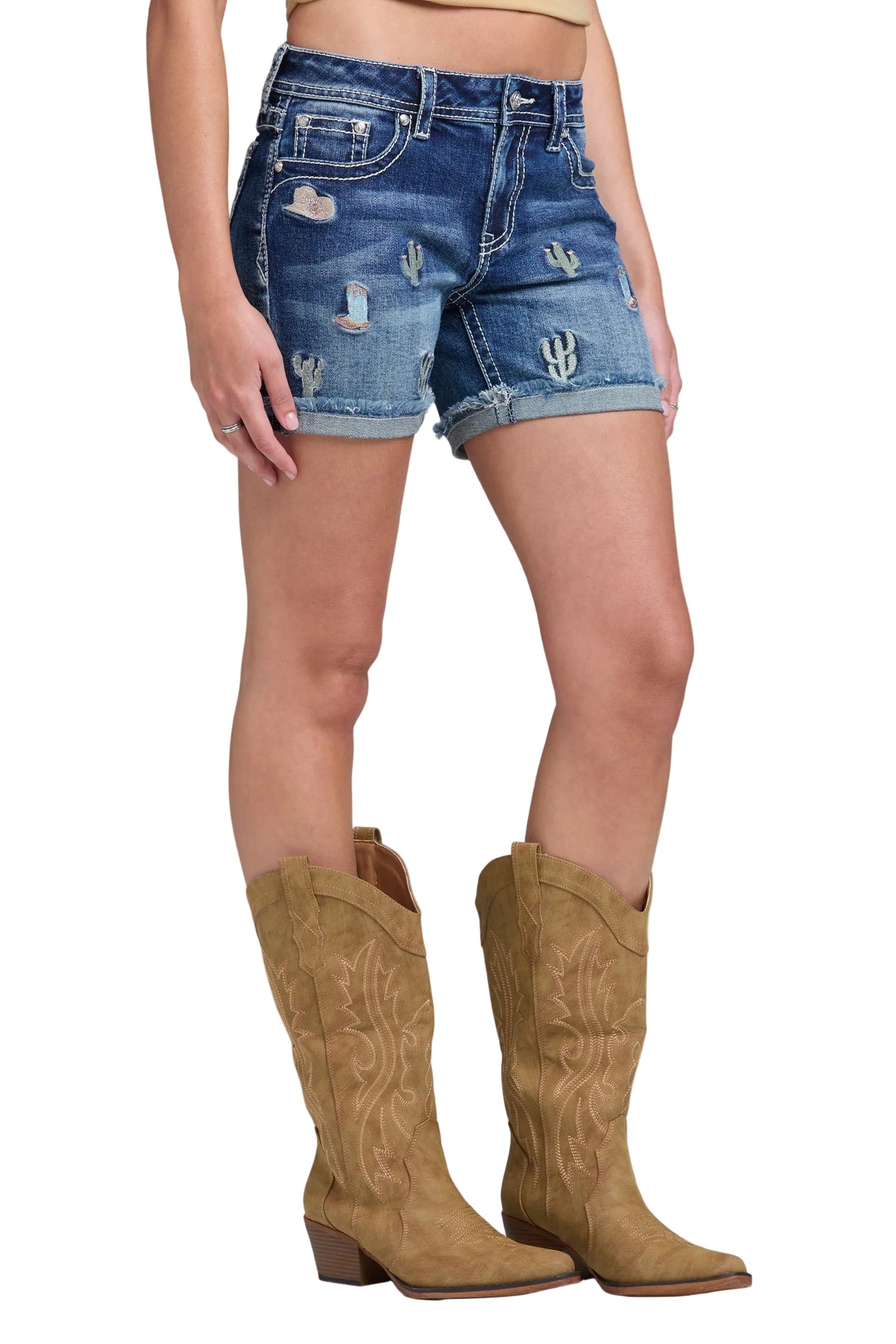 Person wearing distressed denim shorts and brown cowboy boots on a gray background