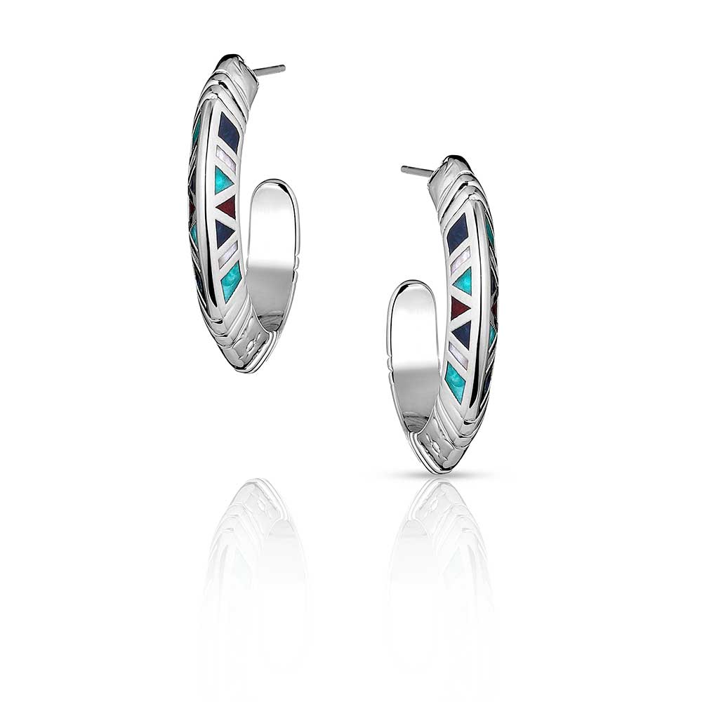 Montana Silversmiths Hidden Mosaic Hoop Earrings. A pair of silver-tone hoop earrings with geometric designs and colorful inlays, resembling turquoise, red agate, lapis, and mother of pearl.