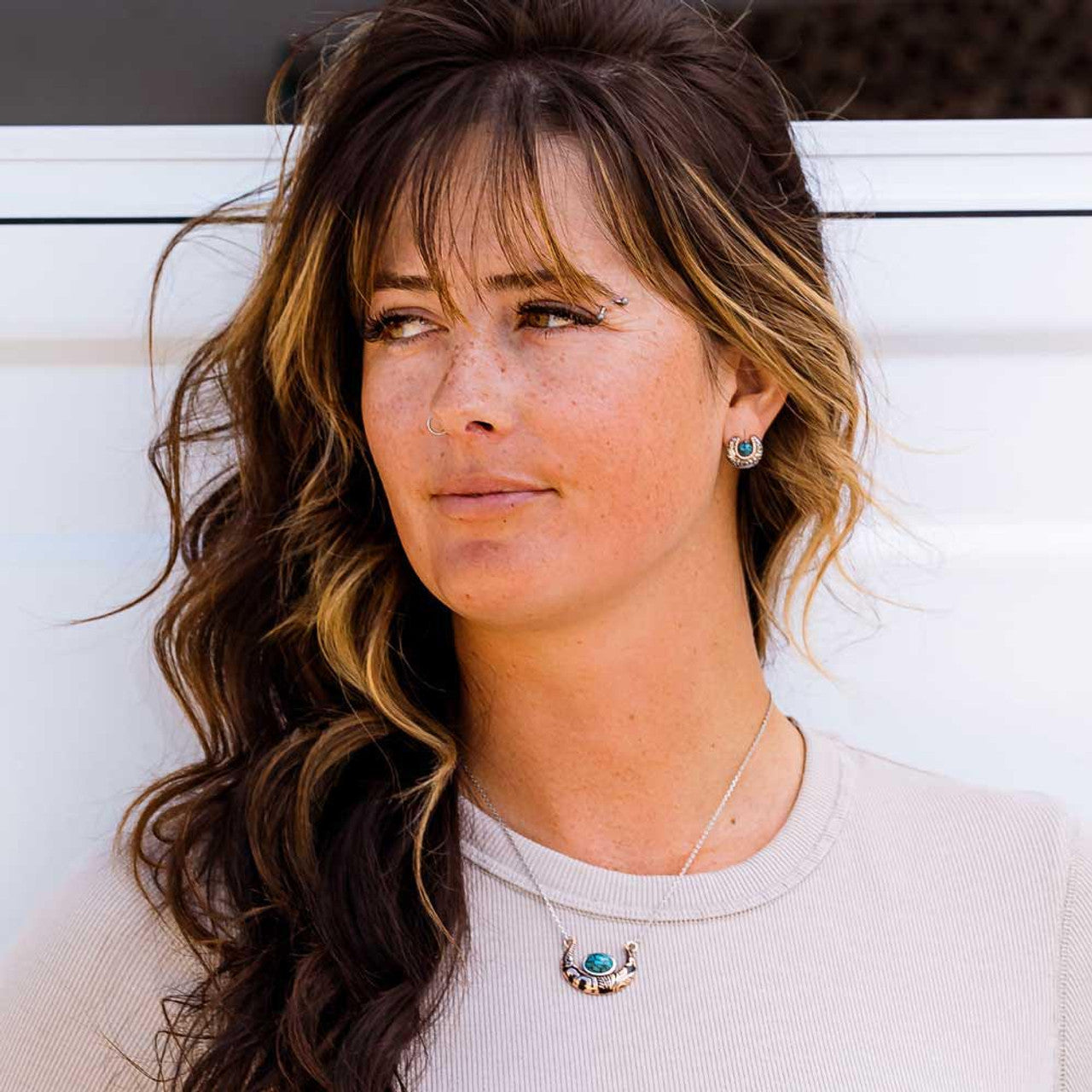 Montana Silversmith Luck of the Pure Earrings. A pair of earrings featuring a silver-tone horseshoe design with a turquoise stone inside and copper-tone rope detail on the inside of the horseshoe.