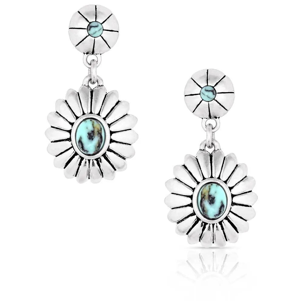 Montana Silversmiths Heyday Blossom Earrings. A pair of silver-colored earrings featuring a small blossom with a crafted turquoise center and a larger blossom with a crafted stone, both with black paint to outline the petals.