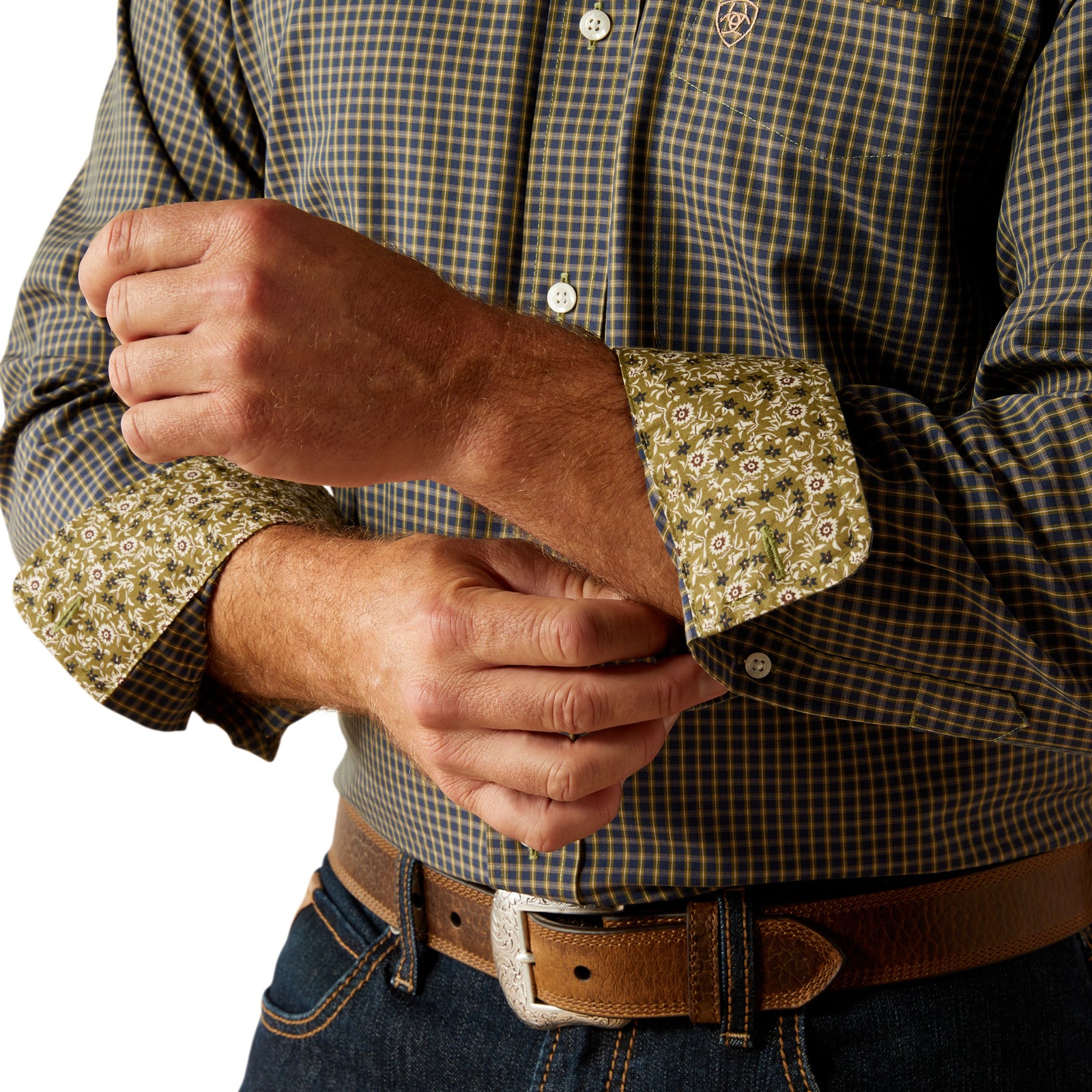 Ariat Men's Wrinkle Free Ferris L/S Western Shirt. Close-up of a person wearing a checkered shirt with floral cuffs, adjusting their shirt.