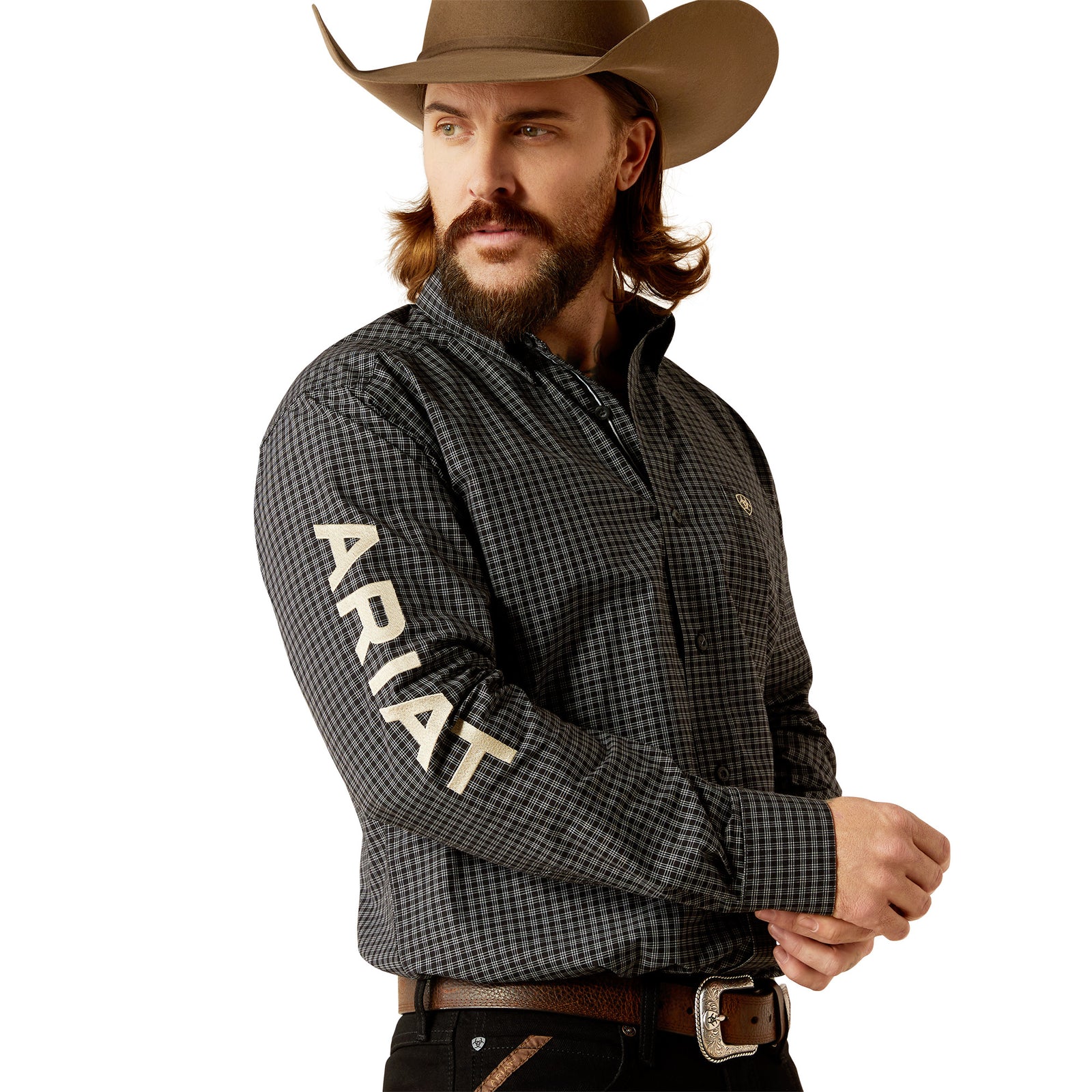 Ariat Men's Pro Series Team Otto L/S Western. A man wearing a long-sleeved checkered Western shirt in black and white, with the brand name 'Ariat' visible on the sleeve, paired with black pants and a cowboy hat.