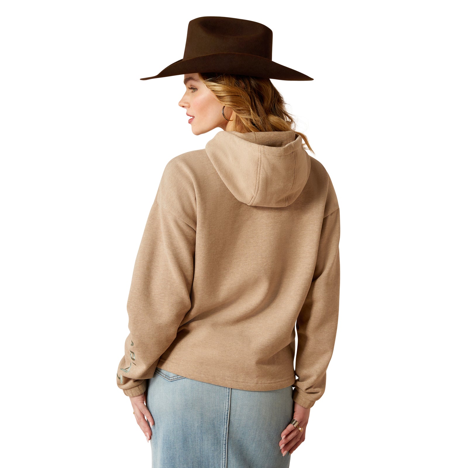 Ariat Women's Essential Logo Hoodie. Person wearing a brown hat and beige hoodie with blue jeans on a white background.
