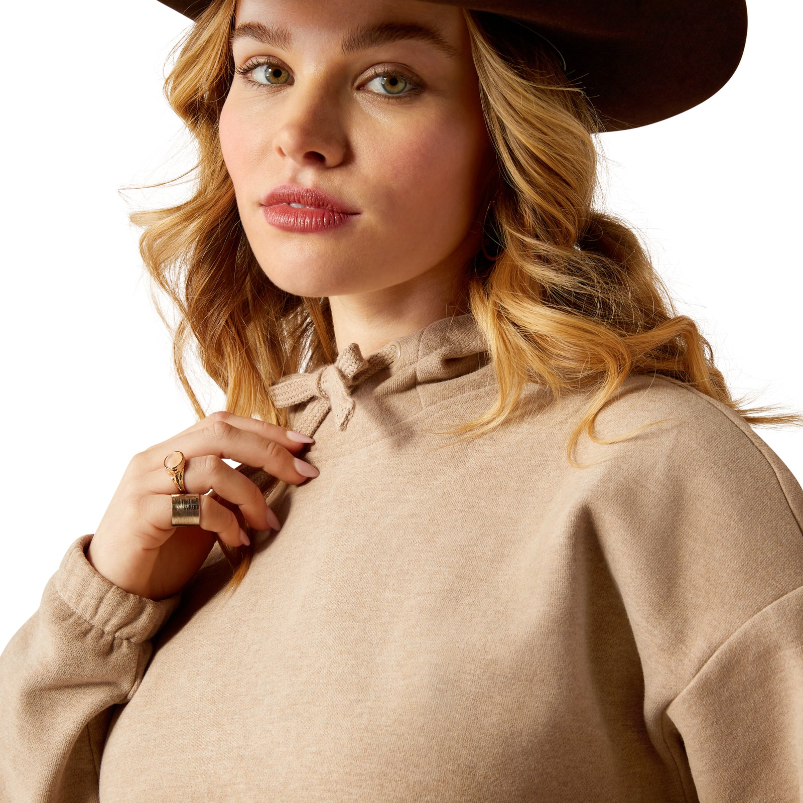 Ariat Women's Essential Logo Hoodie. Woman wearing a beige sweater with a plain background