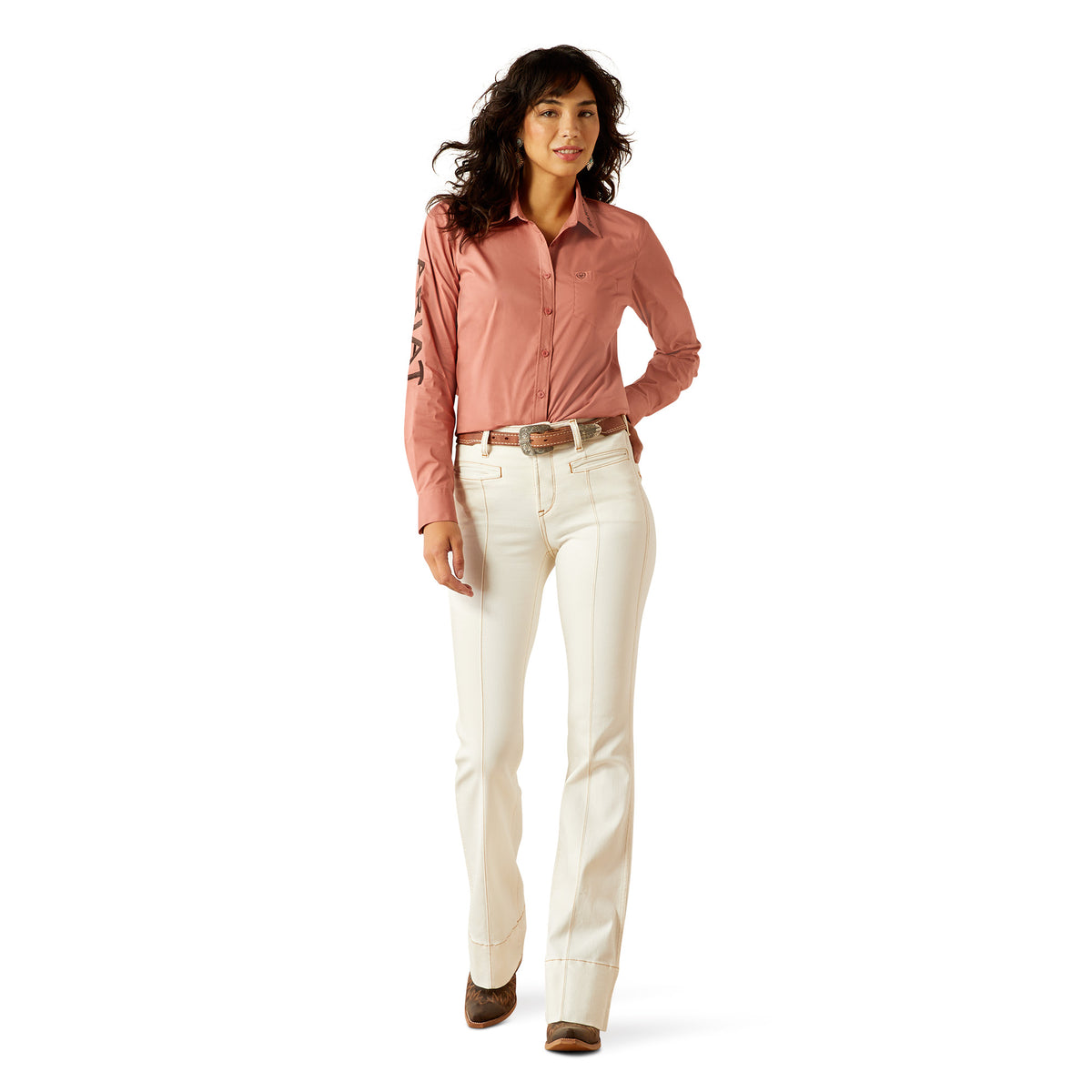 Ariat Women's Wrinkle Resistant Team Kirby L/S Western Shirt. Woman wearing a pink shirt and white pants on a white background