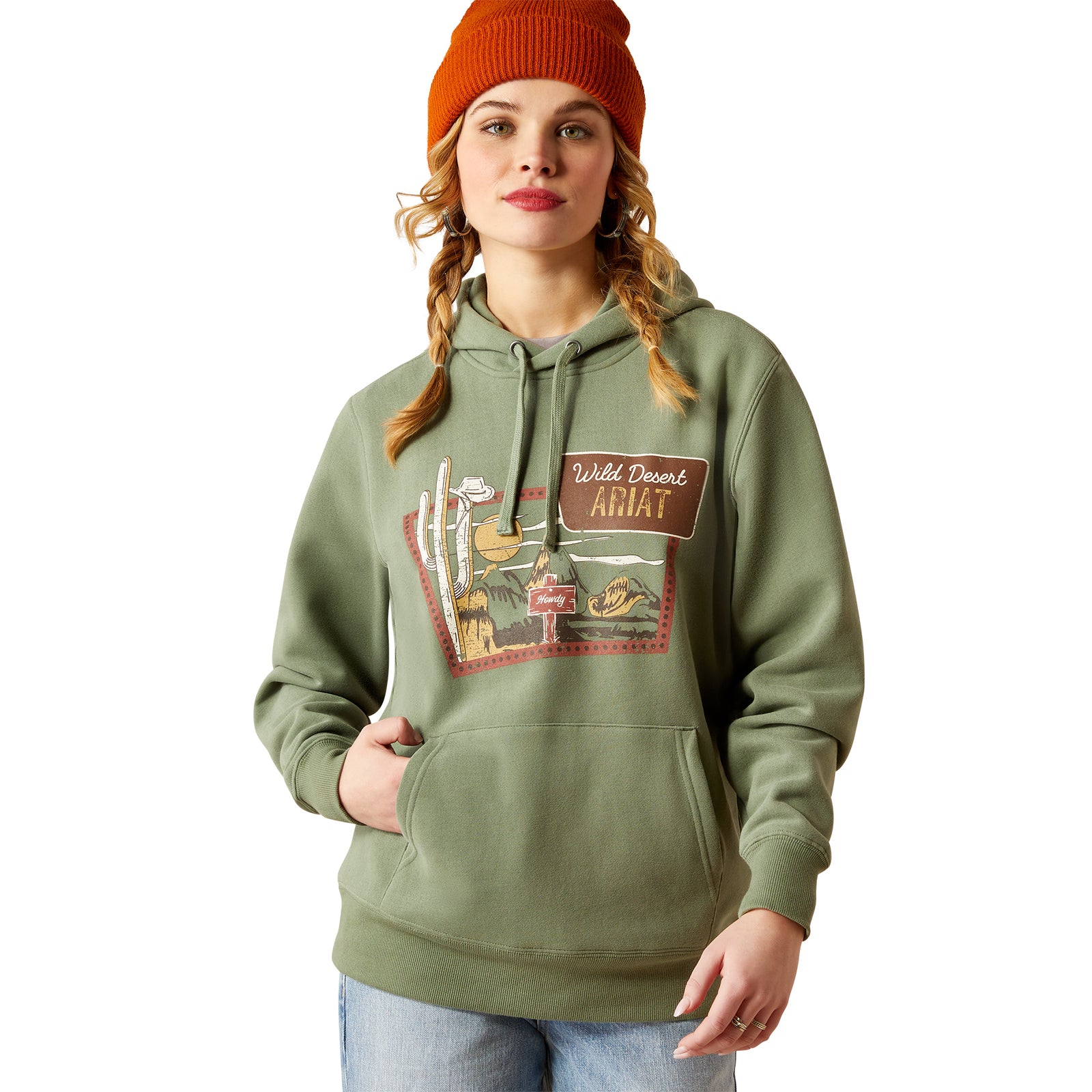 Ariat Women's Route 66 Hoodie. A woman wearing a green hoodie with a graphic print, paired with jeans and an orange beanie.