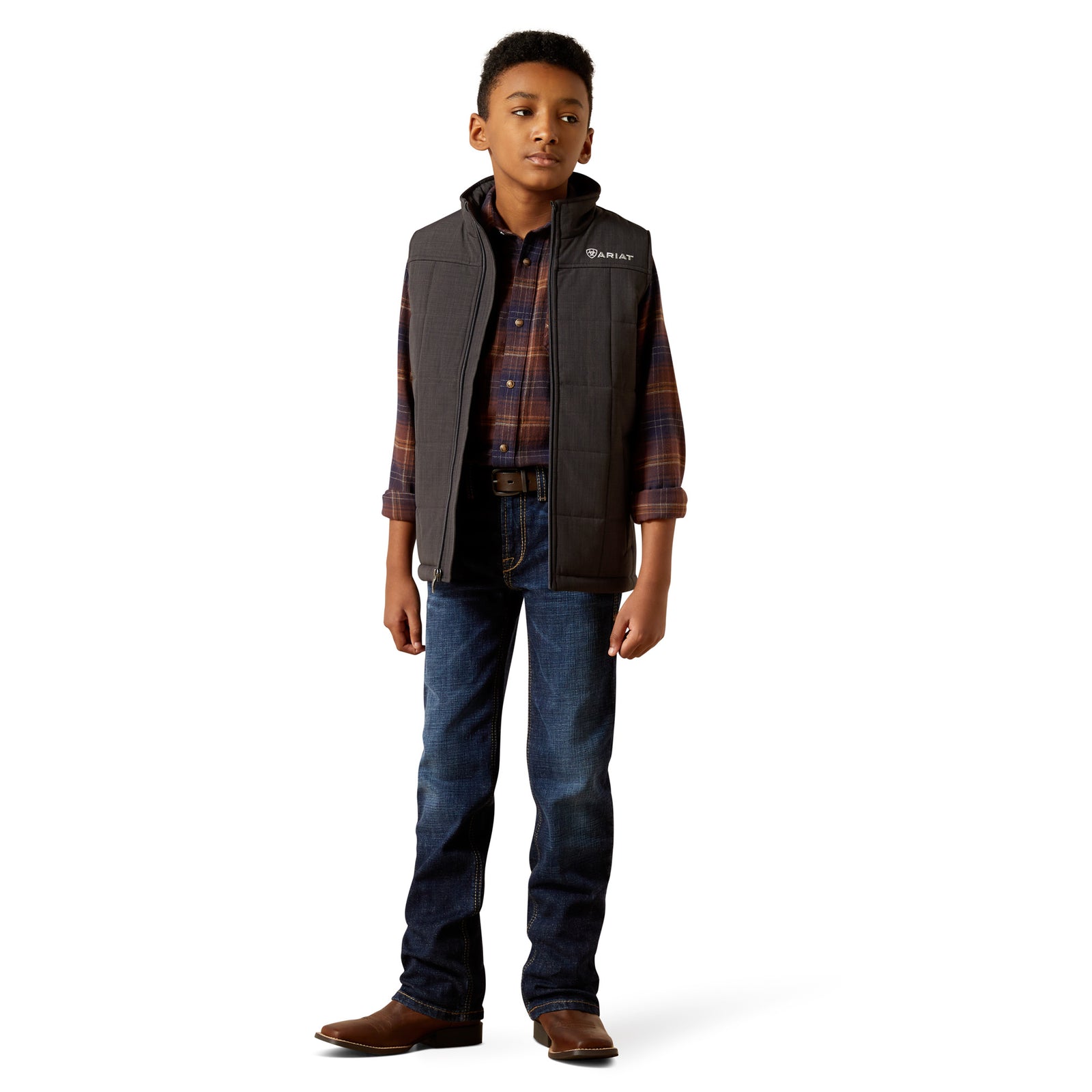 Child wearing a plaid shirt, vest, and jeans on a white background